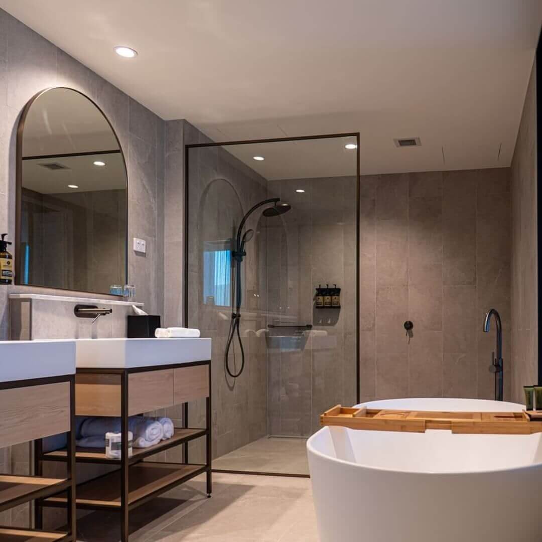 A granite tiled bathroom featuring two vanities and a deluxe deep soaking bath tub